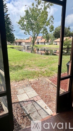 A view from a window looking out to a garden with a pond and houses in the distance.