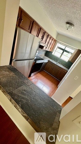 A kitchen with a refrigerator and wooden cabinets.