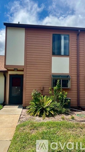 A brown house with a green plant in front.