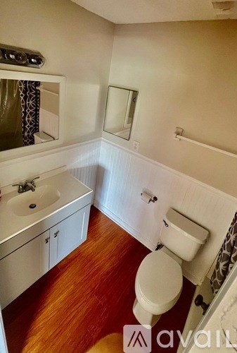 A bathroom with a toilet, sink, and mirror.
