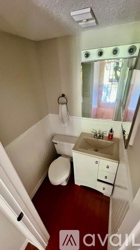 A small bathroom with a toilet, sink, and mirror.
