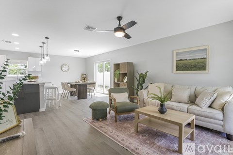 A living room with a white sofa, a wooden coffee table, and a ceiling fan.