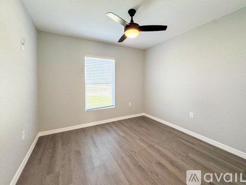 A room with a ceiling fan and a window with blinds.