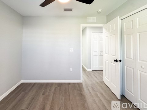 A room with a white door and a ceiling fan.