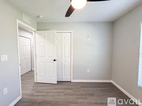 A room with a ceiling fan and three doors.