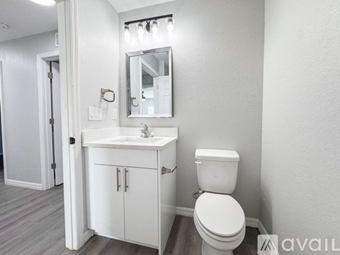 A white bathroom with a toilet, sink, and mirror.