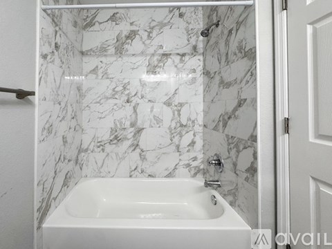 A white bathroom with a marble tile wall and a white sink.