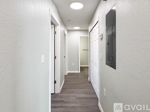 A long hallway with doors on both sides and a sign that says "AVAIL" on the wall.