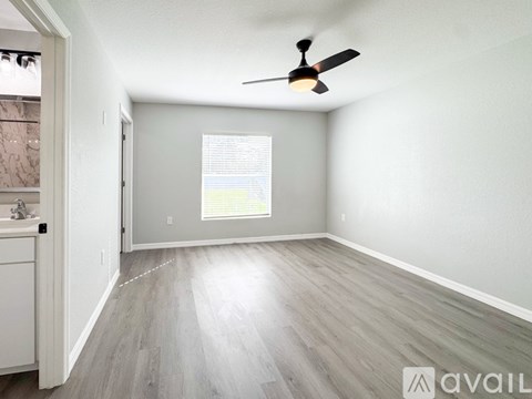 A room with a ceiling fan and a window with blinds.