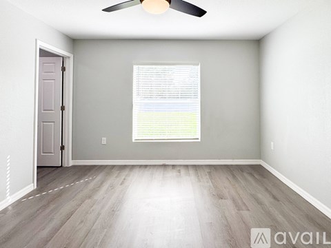 A room with a ceiling fan and a window with blinds.