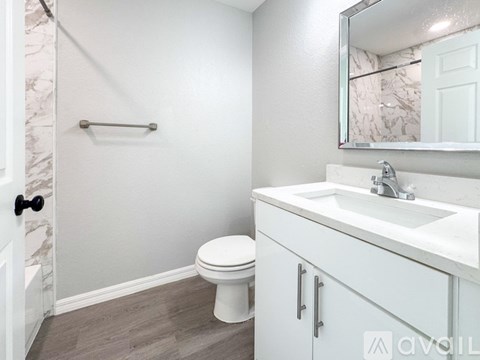 A white toilet sits in a bathroom next to a sink and a mirror.