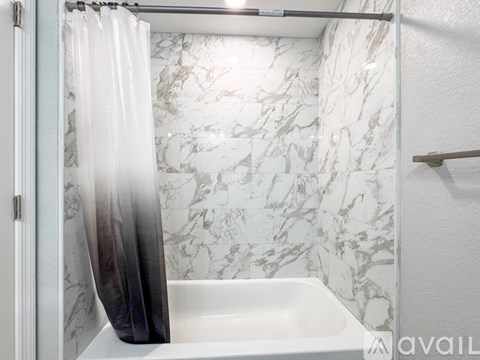 A white marble bathroom with a white sink and shower curtain.