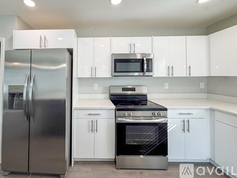 A kitchen with white cabinets and a stainless steel refrigerator.