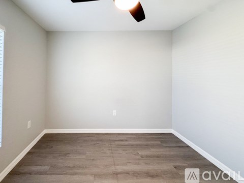A room with a ceiling fan and a window with blinds.