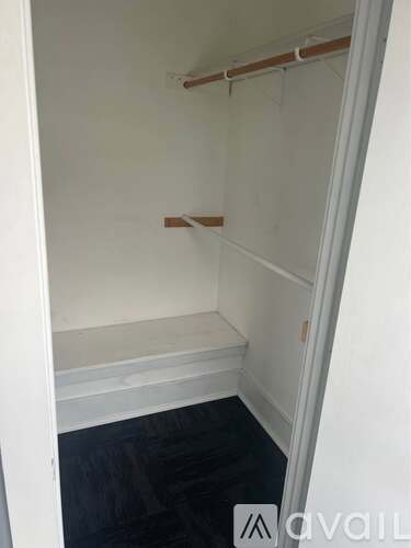 A small, empty room with a white wall and a wooden shelf.