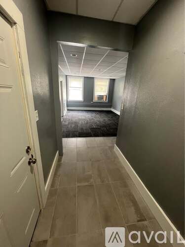 A hallway with a door on the left and a window in the distance.