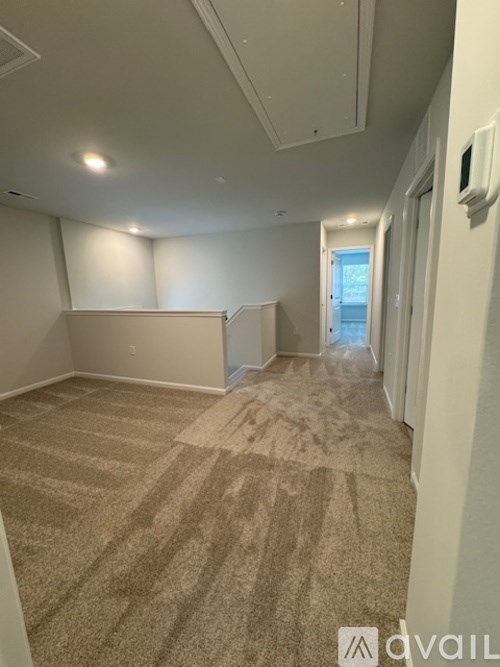 A carpeted room with a doorway leading to another room.