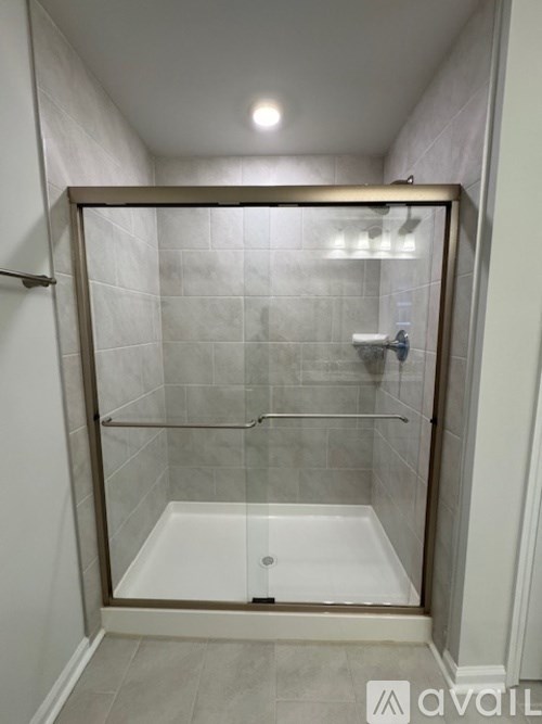 A shower with a glass door and a white tub.