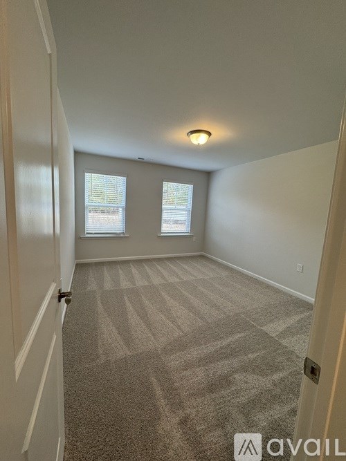 A carpeted room with a door and a window.