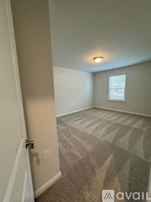 A room with a carpeted floor and a door on the left side.