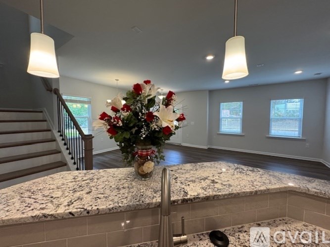 A vase of flowers sits on a countertop in a well-lit room.