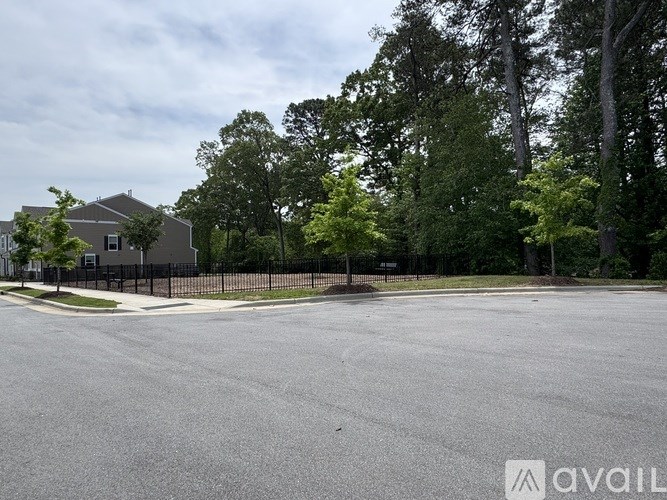 A large, empty parking lot with a building and trees in the background.