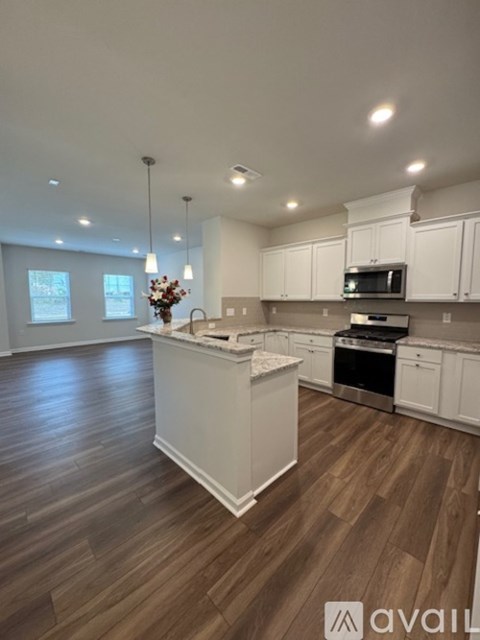 A kitchen with white cabinets and a wooden floor.