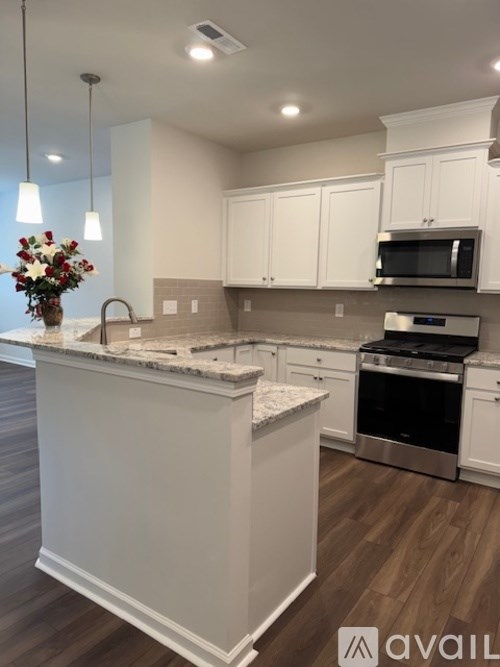 A kitchen with white cabinets and a marble island.