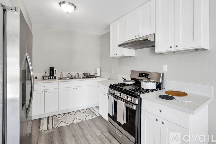 A kitchen with white cabinets and a stainless steel refrigerator.