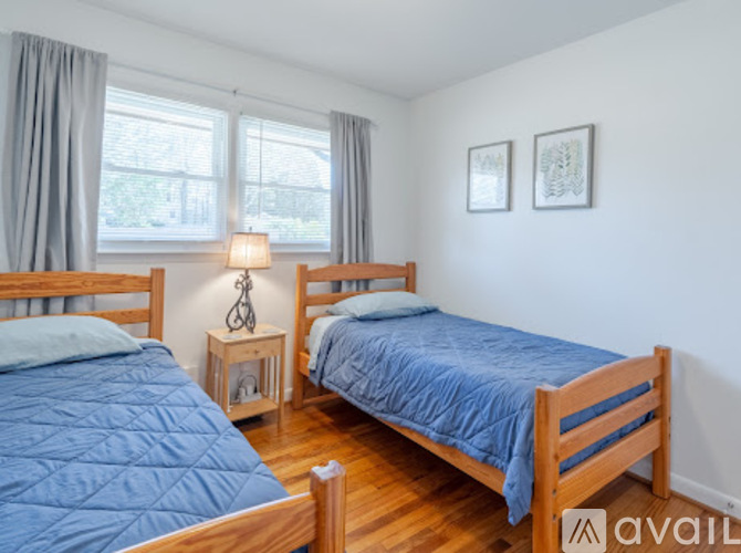 A bedroom with two beds and a nightstand with a lamp.