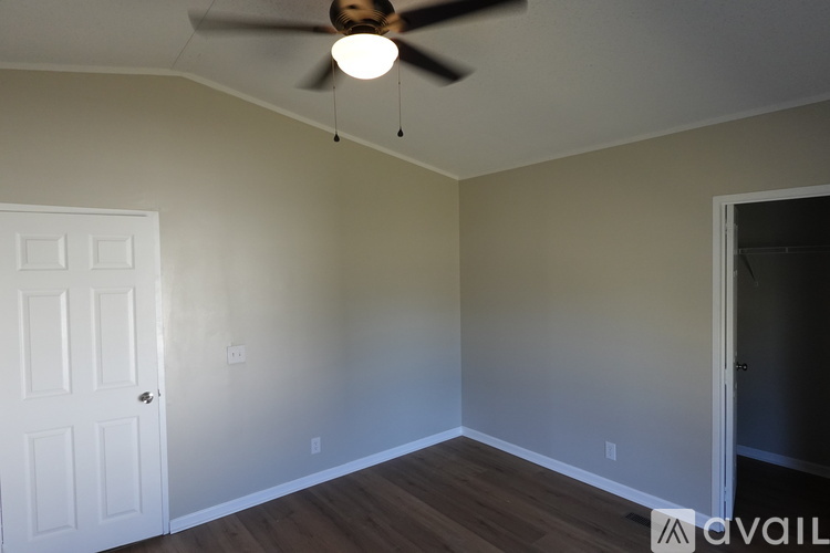 A spacious living room with a ceiling fan and light fixture.