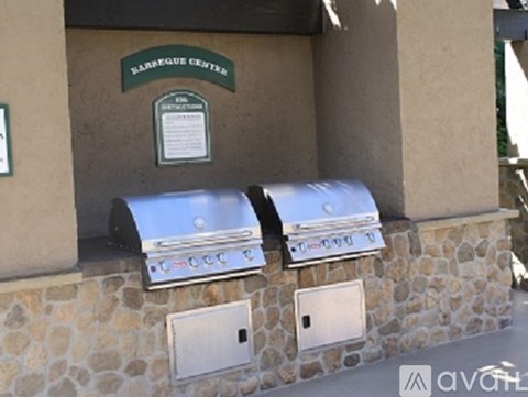 Two barbecue grills are mounted on a stone wall.