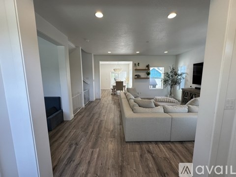 A spacious living room with a white couch and wooden flooring.
