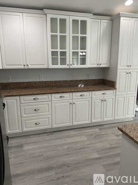 A kitchen with white cabinets and a granite countertop.