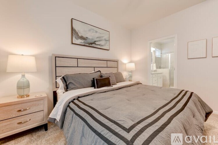 A bedroom with a large bed and a nightstand with a lamp.