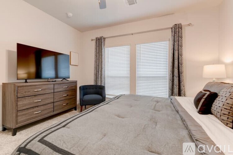 A bedroom with a large bed, a dresser, and a chair.