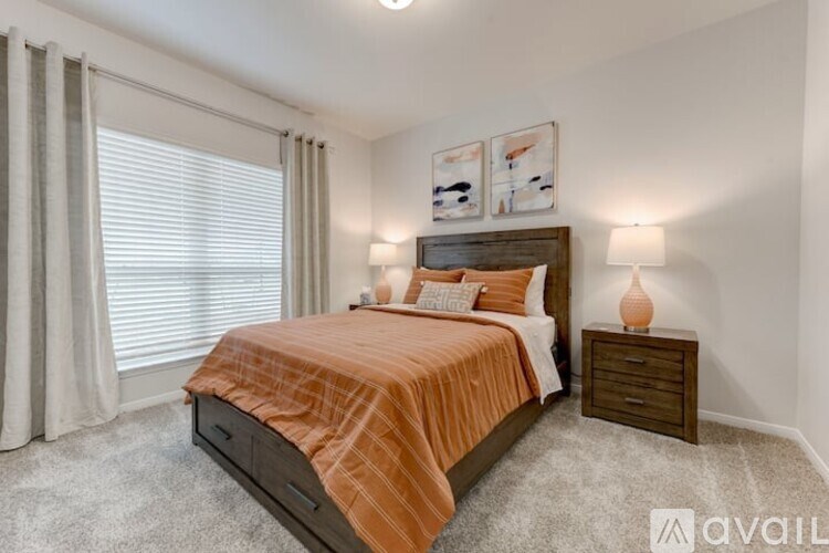 A bedroom with a bed, nightstand, and window with curtains.