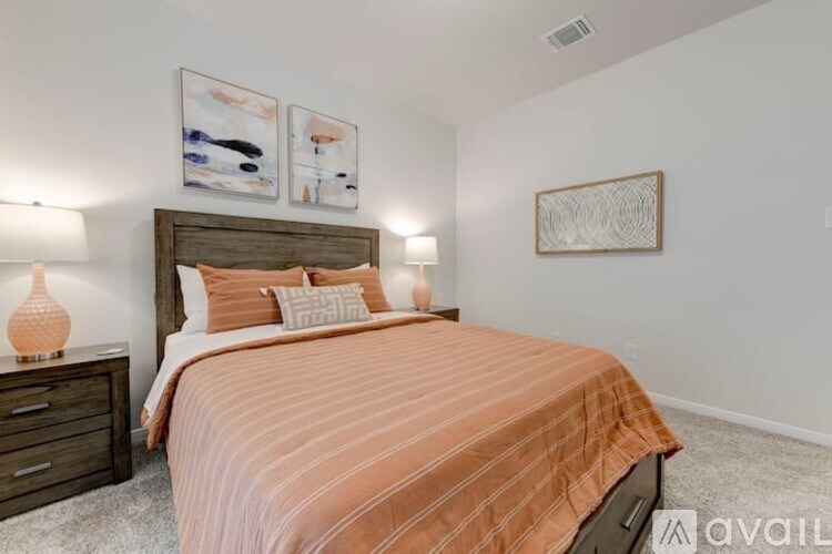 A bedroom with a bed, nightstand, and two wall art pieces.