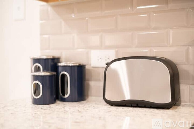 Two blue mugs and a toaster on a countertop.