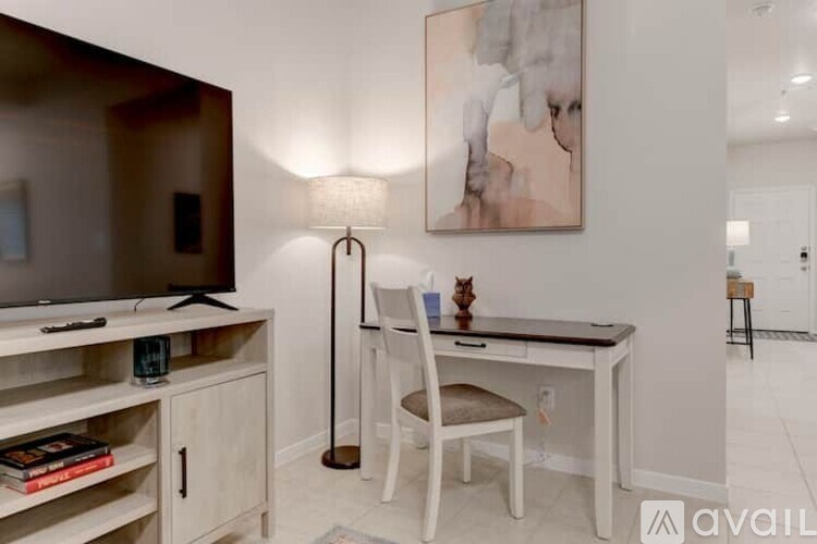 A room with a desk, chair, and a painting on the wall.