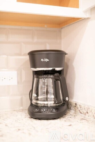 A black Moka pot is on a white countertop.