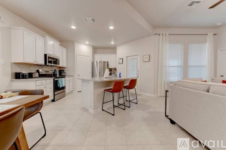 A modern kitchen with white cabinets and a dining area with red chairs.