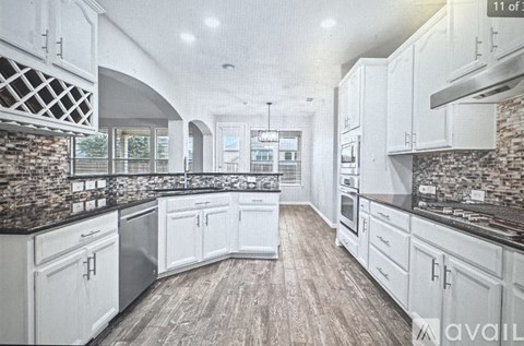 A kitchen with white cabinets and a stone backsplash.