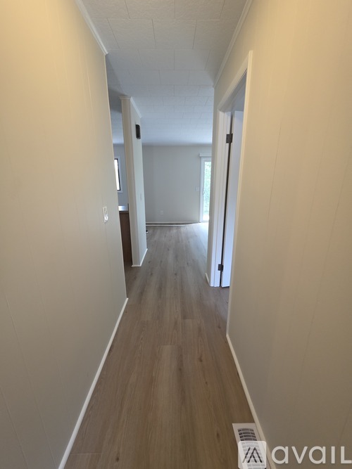 A long hallway with wood floors and white walls.