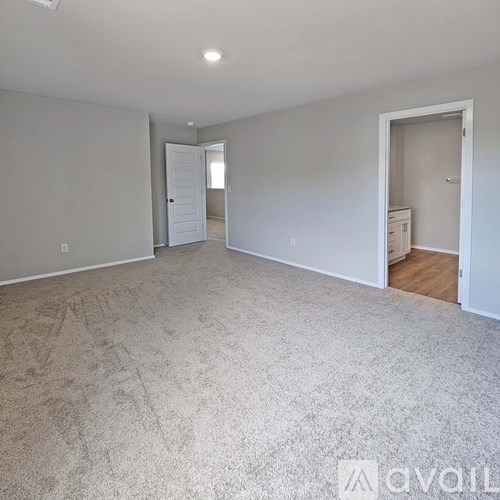 A spacious room with carpeted floor and white walls.