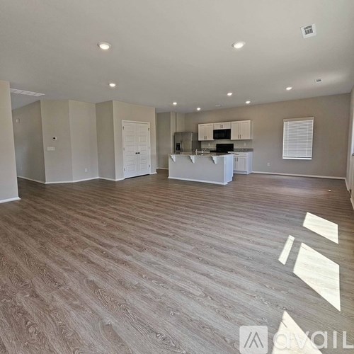 A spacious living room with a kitchen in the background.
