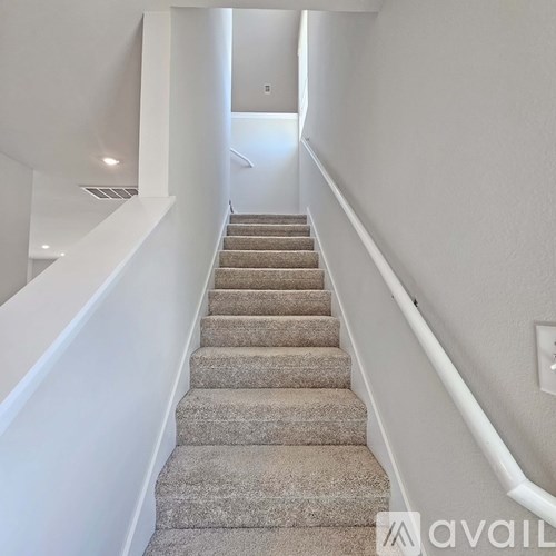 A staircase with beige carpeted steps and white railings.