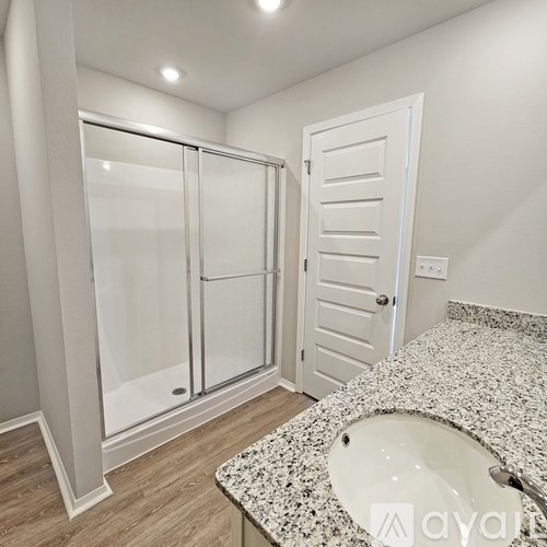 A bathroom with a granite countertop and a walk-in shower.