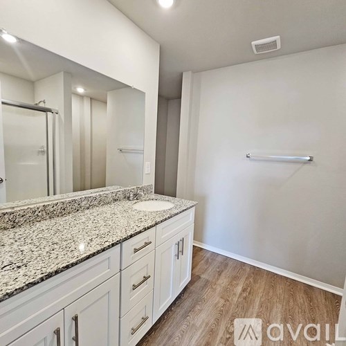 A bathroom with a marble countertop and white cabinets.