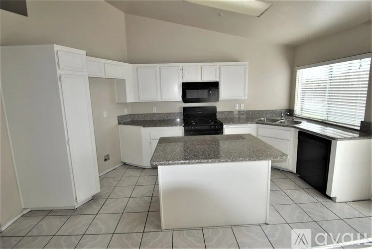 A kitchen with white cabinets and a granite countertop.